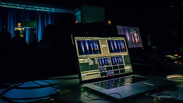 Laptop running live stream software showing the image of a conference stage